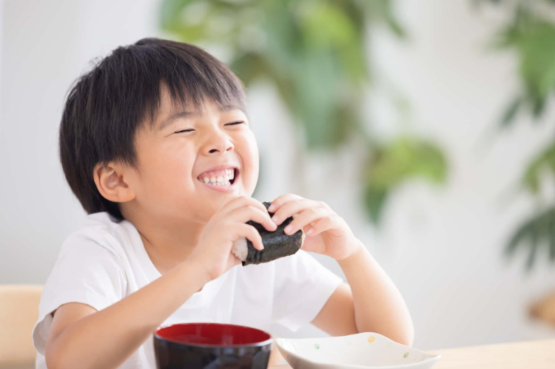 正しい歯みがきで虫歯のない男の子がおにぎりを食べている様子