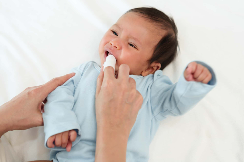 乳児の歯をガーゼでやさしく磨いている様子