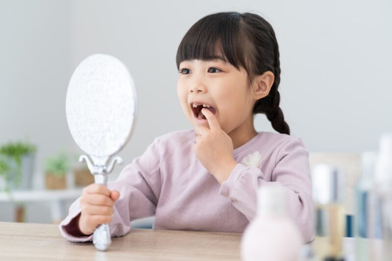 自分の歯を鏡で見る女の子
