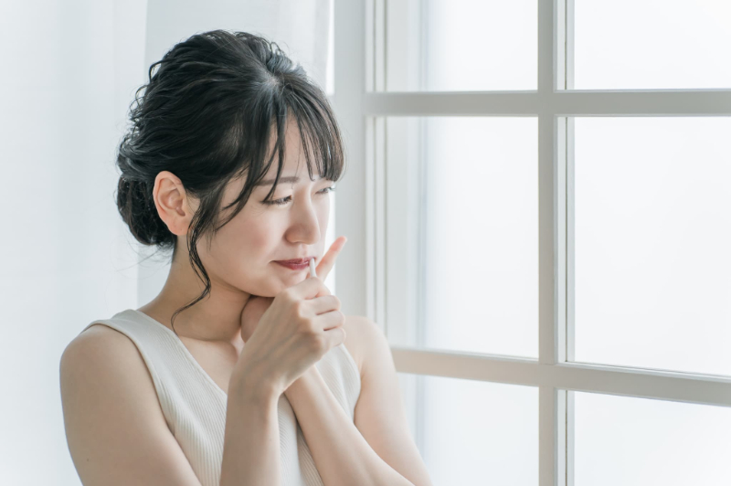 歯磨き時に痛みがあり頬を押さえる女性
