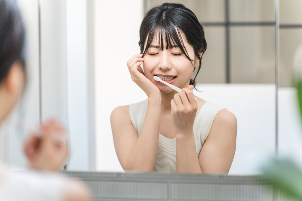 痛む虫歯を手で押さえる歯みがき中の女性